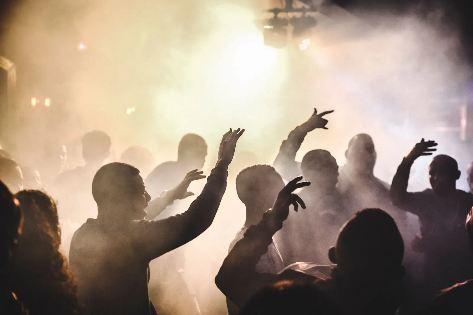 A crowd dancing in silhouette under coloured light