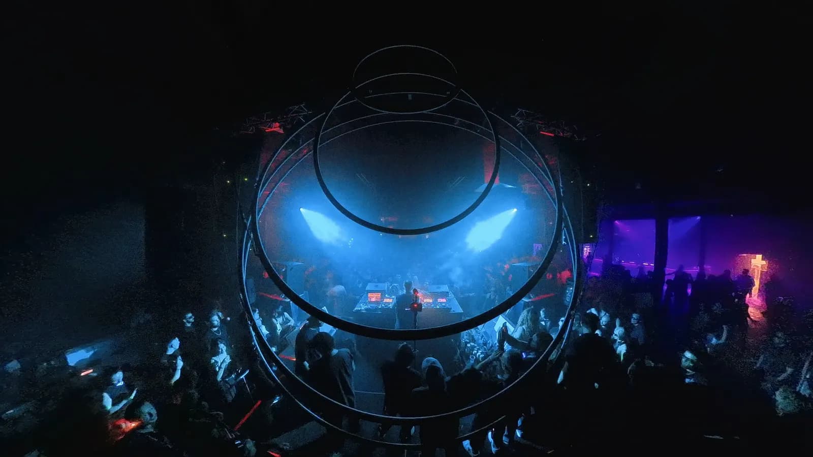 A circular rig suspended over the crowd at Demo Room, lit blue from inside