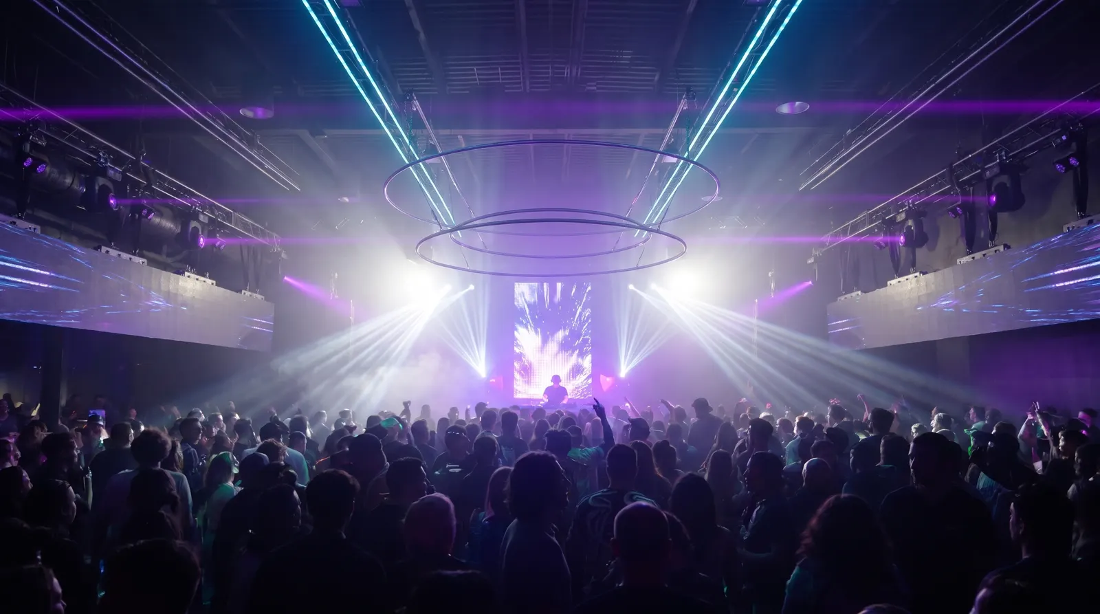 Demo Room from the back of the crowd, white beams and a video wall under two suspended rings
