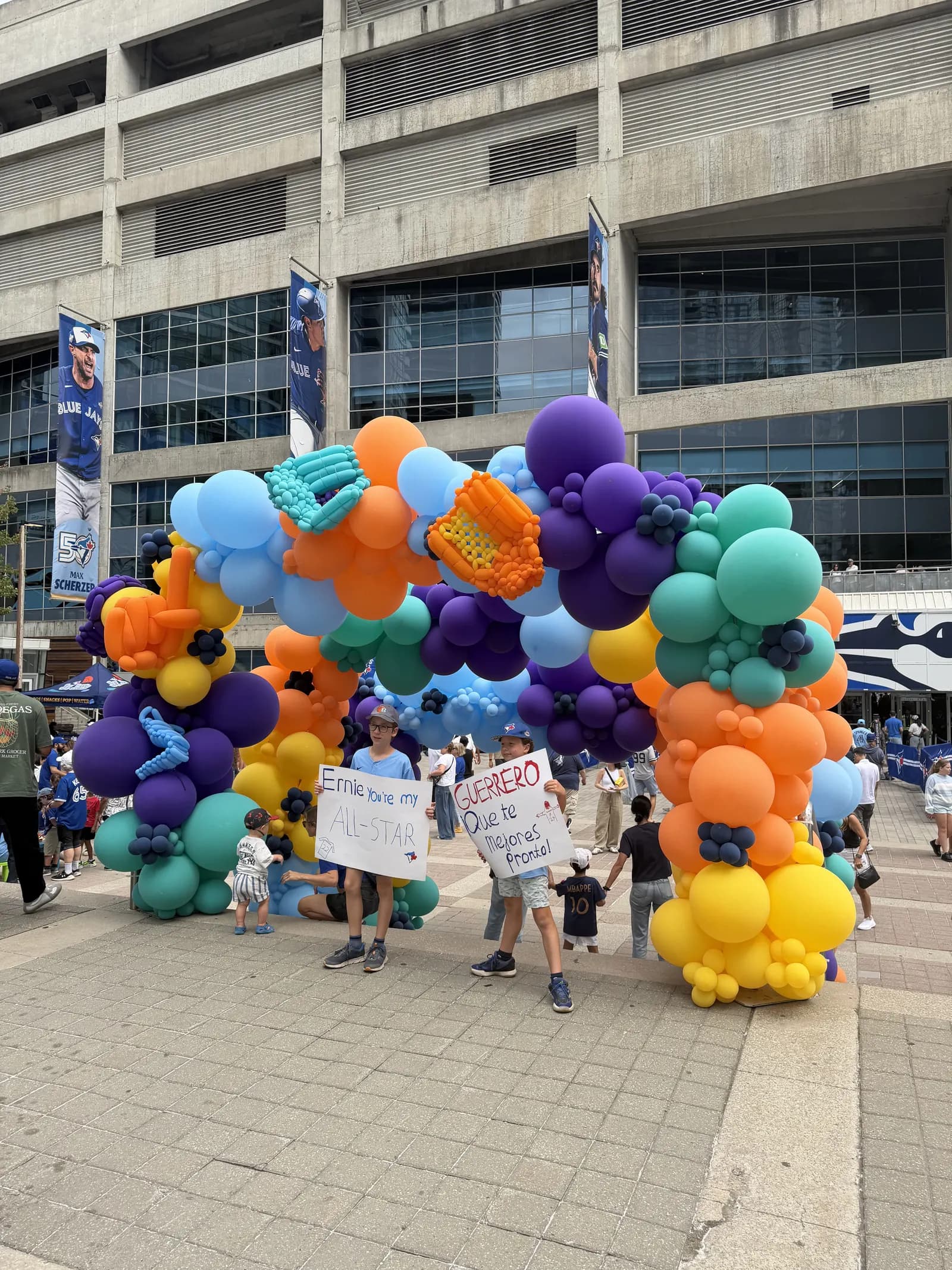 A balloon arch in team colours over a stadium entrance, fans walking under it