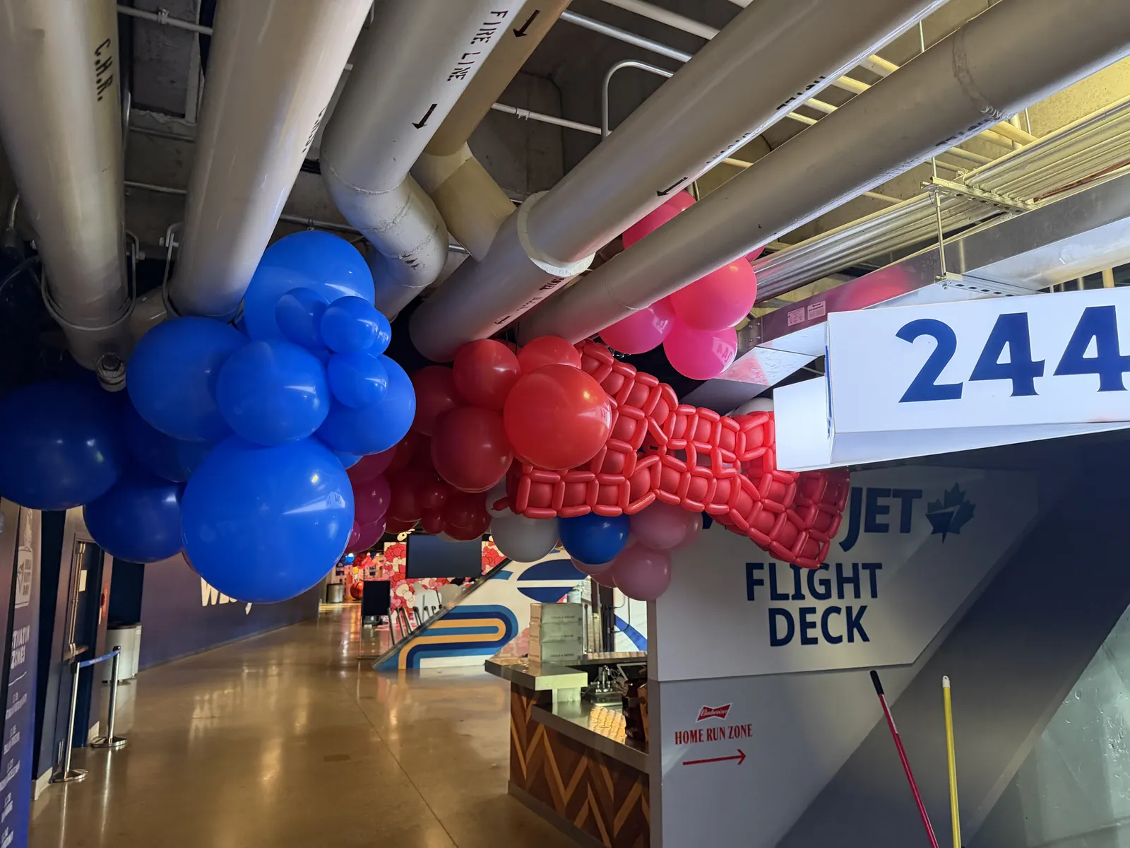 A red and blue balloon garland along a stadium concourse beside the Flight Deck sign